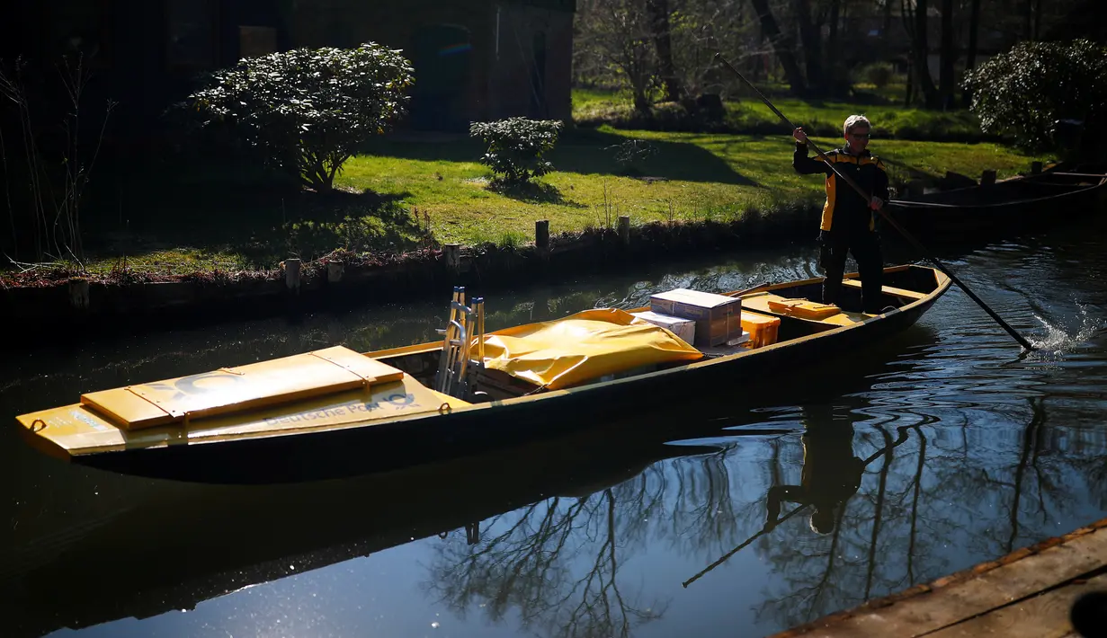 Tukang pos wanita dari Deutsche Pos DHL, Andrea Bunar menggunakan perahu tradisional untuk mengantar surat dan paket di desa Spreewald di Lehde, Jerman, 4 April 2019. Andrea Bunar menggunakan perahu untuk mengantar surat setiap bulan April hingga Oktober. (REUTERS/Hannibal Hanschke)