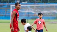 Pemain PSM Makassar, Ferdinand Sinaga, berlatih ditemani oleh buah hatinya. (Bola.com/Abdi Satria)