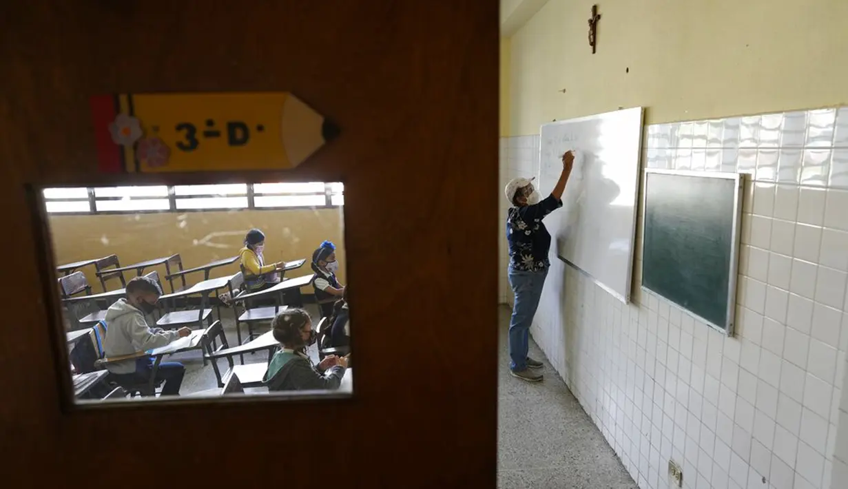 Para siswa menghadiri kelas pada hari pertama kembali ke sekolah tatap muka sejak dimulainya pembatasan pandemi COVID-19, di sekolah umum di Caracas, Venezuela, 25 Oktober 2021. (AP Photo/Ariana Cubillos)