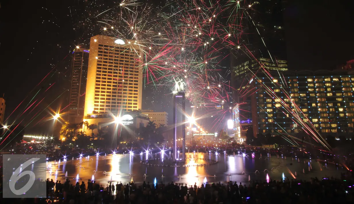 Warga saat menikmati malam tahun baru dengan dengan pertunjukan kembang api di Bundaran HI, Jakarta, Jumat (1/1/2016) malam. Kemeriahan kembang api tersebut merupakan bentuk perayaan pergantian tahun 2015 menuju 2016. (Liputan6.com/Angga Yuniar)