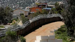Seniman asal Kanada, Cosimo Cavallaro membangun dinding perbatasan menggunakan keju di perbatasan Amerika dan Meksiko, dekat Tecate, California, 28 Maret 2019. Balok yang digunakan untuk membuat tembok tersebut terbuat dari keju keras dan masing-masing seharga USD 100. (REUTERS/Mike Blake)