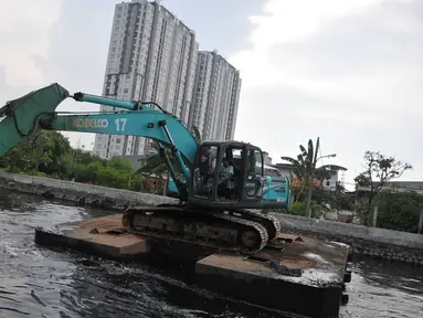 Petugas mengoperasikan eskavator untuk mengeruk lumpur di Kali Sunter Podomoro, Jakarta, Jumat (4/12). Pemprov DKI bersama Kementrian PU melakukan pembebasan bantaran sungai. (Liputan6.com/Gempur M Surya)