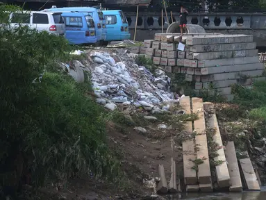 Seorang anak bermain dekat tiang pancang untuk pembangunan dinding turap di Kali Ciliwung, Rawajati, Kalibata, Jakarta, Jumat (25/9/2020). Tumpukan tiang pancang untuk pembangunan dinding turap sebagai bagian dari proyek normalisasi Kali Ciliwung itu tampak terbengkalai. (merdeka.com/Imam Buhori)