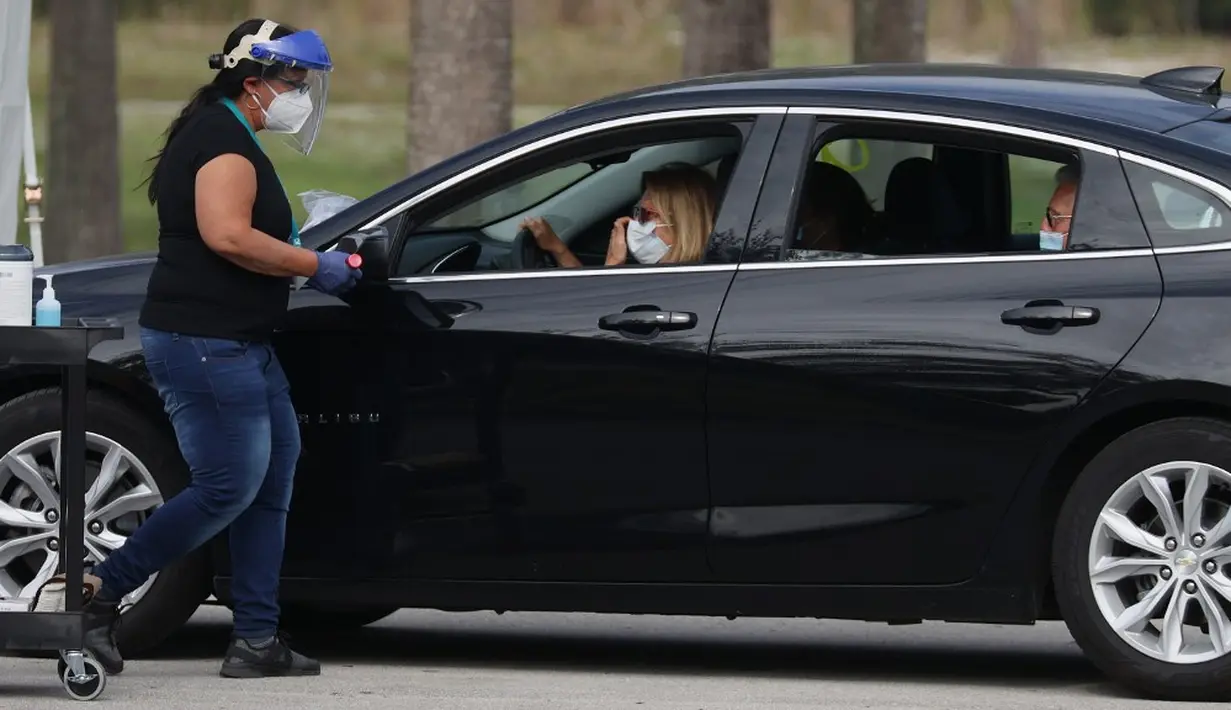 Petugas kesehatan memeriksa warga sebelum mengarahkan ke area vaksinasi COVID-19 drive-thru di Vista View Park, Davie, Florida, Amerika Serikat, 4 Januari 2021. Lokasi vaksinasi COVID-19 drive-thru tersebut disiapkan untuk penduduk Broward yang berusia 65 tahun ke atas. (Joe Raedle/Getty Images/AFP)