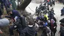 Ribuan migran menyeberangi sungai dengan berpegangan pada seutas tali di perbatasan Yunani-Makedonia, Idomeni, Yunani (14/3/2016). Lebih dari 1.000 migran nekat menembus sungai untuk mencari jalan keluar perbatasan. (Reuters/Stoyan Nenov)