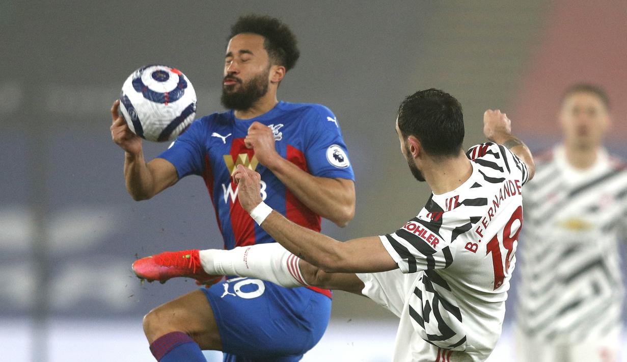 Gelandang Manchester United, Bruno Fernandes berusaha merebut bola dari pemain Crystal Palace, Andros Townsend pada pertandingan lanjutan Liga Inggris di stadion Selhurst Park di London, Kamis (4/3/2021). MU bermian imbang atas Crystal Palace 0-0. (Adrian Dennis/Pool via AP)