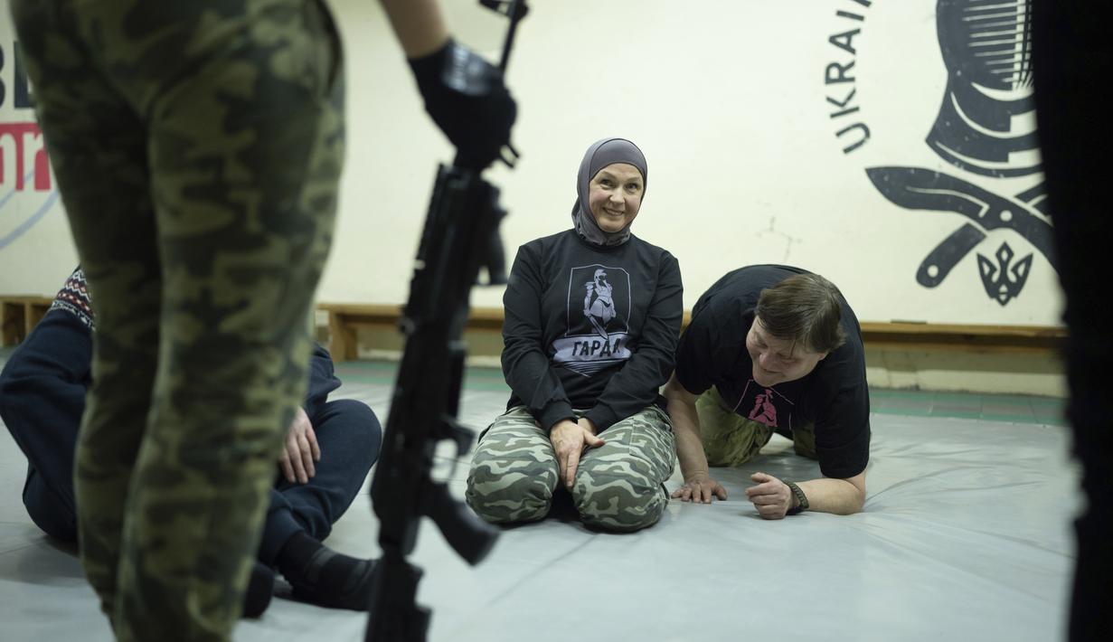 Svetlana Putilina tersenyum saat mendengarkan instruktur selama pelatihan di Kharkiv, Ukraina (30/1/2022). Dengan tekad yang kuat dan tidak sedikit pun panik, wanita berusia 50 tahun itu telah mengatur rencana darurat untuk keluarganya dan unitnya. (AP Photo/Evgeniy Maloletka)