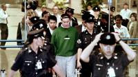 Nick Leeson tiba di bandara Changi Singapura dikelilingi oleh petugas polisi setempat pada 23 November 1995 setelah diusir oleh Jerman untuk diadili atas tuduhan penipuan dan pemalsuan atas runtuhnya Bank Barings Inggris pada Februari 1995. (AFP/JOHN MACDOUGALL)