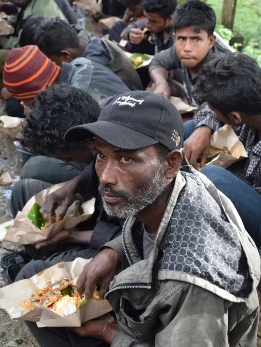 Sejumlah warga Rohingyah menikmati makanan di sbuah pos Lanal Kuala Idi, Aceh Timur (4/12). Menurut pihak berwenang, para pengungsi Rohingya mendarat ke perairan Idi dengan menggunakan perahu tepat pukul 08.00 WIB. (AFP Photo/Cek Mad)
