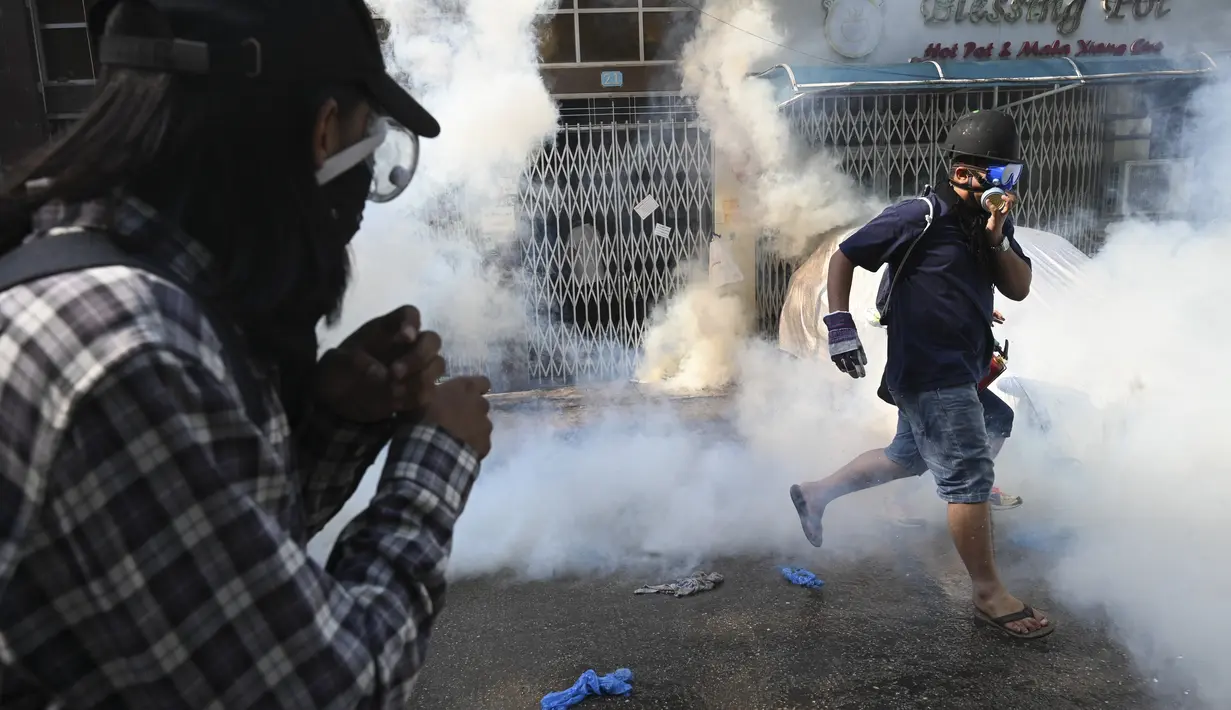 Para pengunjuk rasa lari setelah gas air mata ditembakkan selama demonstrasi menentang kudeta militer di Yangon (9/3/2021). Bentrokan warga anti kudeta militer dengan aparat keamanan Myanmar masih terus berlangsung. (AFP/STR)