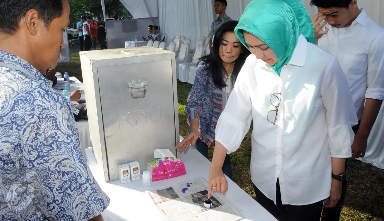 Calon Walikota Tangerang Selatan, Airin Rachmi Diany bersama putra pertama, TB Ghifari Wardana mencelupkan jari ke botol berisi tinta usai menggunakan hak pilih di TPS 17 Serpong Utara, Tangerang Selatan, Banten, Rabu (9/12). (Liputan6.com/Helmi Afandi)