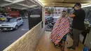 Gerardo (kanan) memangkas rambut pelanggan dalam salon rambut keliling miliknya di Mexico City, Meksiko, 6 Agustus 2020. Gerardo mengubah sebuah mobil van menjadi salon rambut keliling yang menawarkan jasa pangkas rambut kepada warga Mexico City di tengah pandemi COVID-19. (Xinhua/Ricardo Flores)