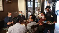 Pramusaji menggunakan pelindung wajah, masker dan sarung tangan saat melayani pelanggan di The Atjeh Connection Coffee and Resto, Jakarta, Senin (8/6/2020). Tempat ini siap menerapkan protokol kesehatan dalam menerapkan tatanan kehidupan baru atau ‘new normal’. (Liputan6.com/Faizal Fanani)