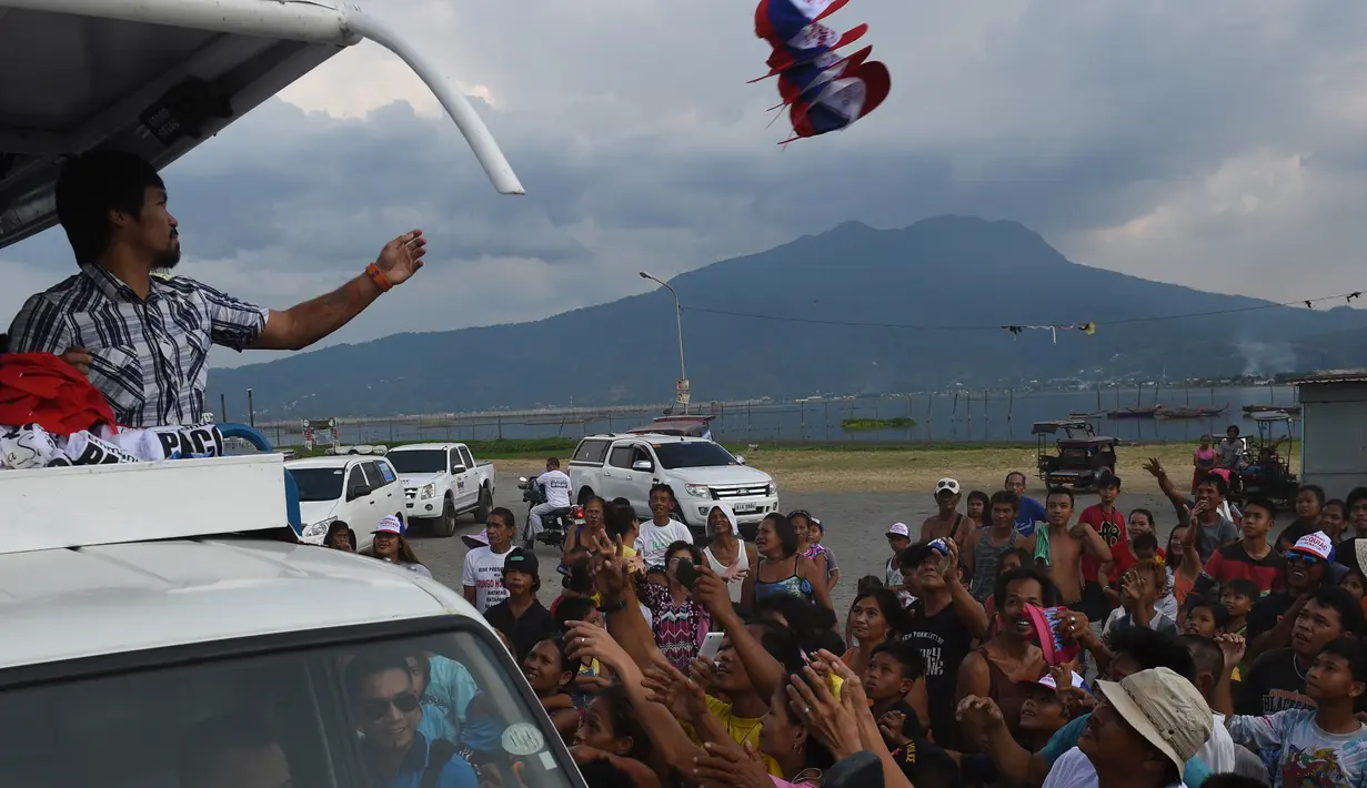 Manny Pacquiao melempar topi ke pendukungnya selama kampanye di kota Calamba, Provinsi Laguna, selatan Manila (28/4). Manny Pacquiao menjadi salah satu politisi Filipina yang paling kuat di negaranya. (AFP PHOTO/TED aljibe)