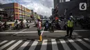 Petugas mengatur lalu lintas untuk warga menyeberang jalan menggunakan pelican crossing di kawasan Glodok, Jakarta, Sabtu (22/1/2022). Halte Glodok baru merupakan halte lama yang terdampak proyek pembangunan MRT Fase II. (Liputan6.com/Johan Tallo)