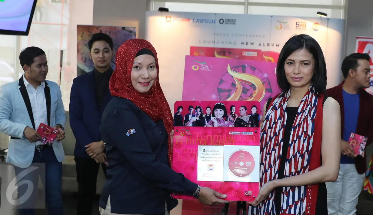 Linda Wibisono, Head of Local Acquisition Department Indosiar (kiri) memberikan pelakat ke pihak Trinity Optima Production yang di wakilkan oleh Rizki Utami usai peluncuran VCD Karaoke di Jakarta, Kamis (6/10). (Liputan6.com/Herman Zakharia)