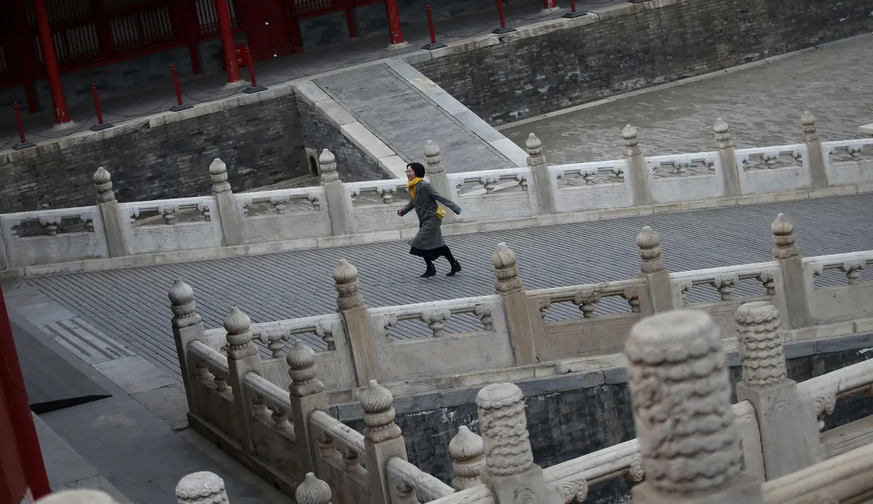 Seorang wanita berjalan saat melakukan tur ke Kota Terlarang di Beijing, (7/3). Kota Terlarang, merupakan istana terisolasi kaisar Qing dan Dinasti Ming China untuk tempat wisata utama yang terletak di pusat ibu kota. (AP Photo/Aijaz Rahi)