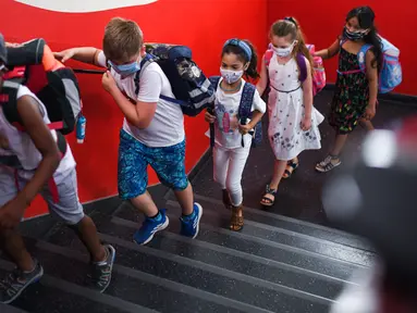 Siswa dengan masker menaiki tangga menuju ruang kelas mereka di sekolah dasar Petri di Dortmund, Jerman, Rabu (12/8/2020). Para siswa di negara bagian Jerman, North Rhine-Westphalia, harus mengenakan masker setiap waktu ketika mereka kembali ke sekolah pada Rabu ini. (Ina FASSBENDER/AFP)