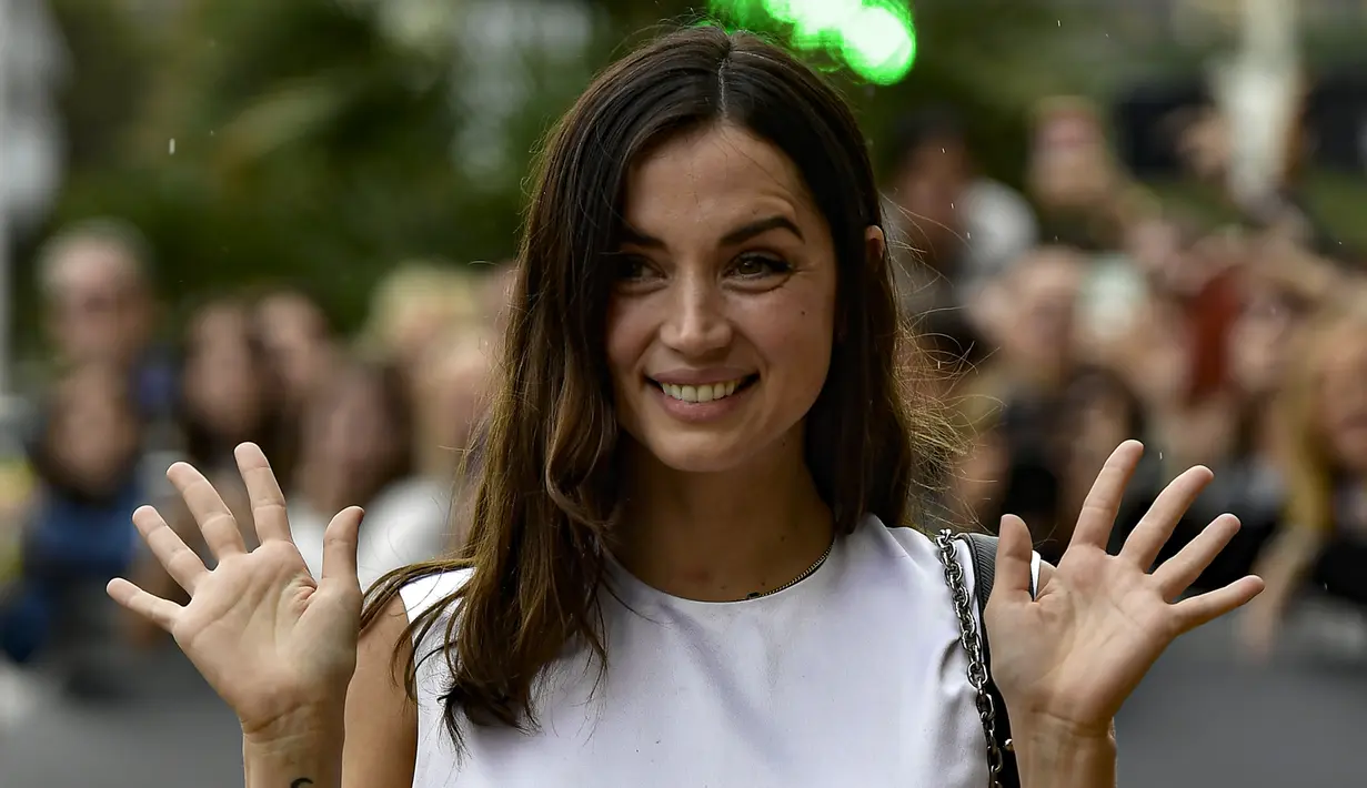 <p>Ana de Armas menyapa penggemarnya saat tiba menghadiri Festival Film San Sebastian ke-70, di San Sebastian, Spanyol utara (23/9/2022). Ana tambil cantik mengenakan dress putih bergaya klasik. (AP Photo/Alvaro Barrientos)</p>