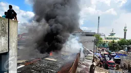 Asap hitam membumbung tinggi akibat kebakaran yang melanda Pasar Kanjengan Semarang yang masih satu kompleks dengan Pasar Johar, Sabtu (18/6). Sejumlah mobil pemadam kebakaran dikerahkan memadamkan belasan toko di kompleks pasar itu. (Liputan6.com/Gholib)