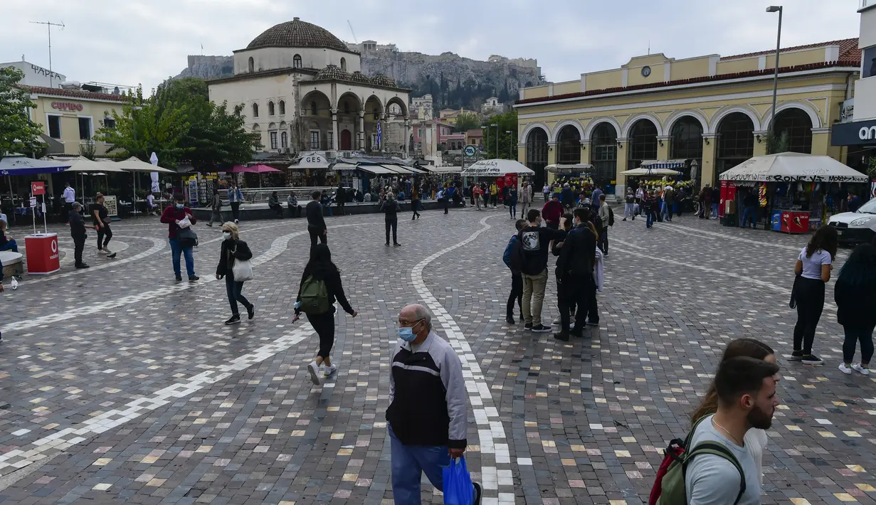 Pejalan kaki, beberapa mengenakan masker, berjalan di Monastiraki square, Athena, Selasa (9/11/2021). Yunani melaporkan rekor tertinggi baru kasus COVID-19 harian pada Senin ketika janji vaksinasi melonjak setelah pembatasan baru untuk warga yang tidak divaksinasi dimulai (AP Photo/Michael Varaklas)