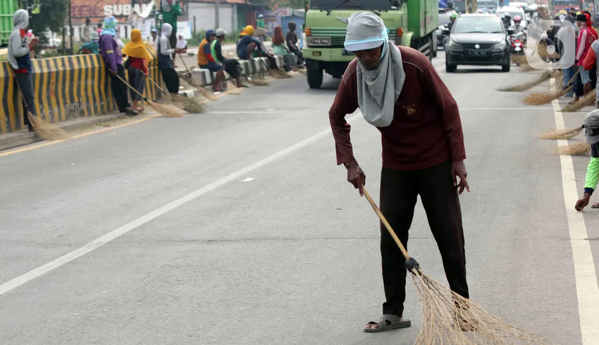 <p>Seorang warga mengambil sedekah pemberian pengendara kendaraan bermotor dengan menggunakan sapu di kawasan Jembatan Sewo, Indramayu, Jawa Barat, Jumat (29/4/2022). Aksi mengambil uang sedekah menggunakan sapu meningkat saat puncak arus mudik. (Liputan6.com/Herman Zakharia)</p>
