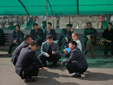 Sejumlah pria Korea Utara berbincang di luar supermarket di pusat kota Pyongyang, Korea Utara, (21/10).  (AP Photo / Dita Alangkara)