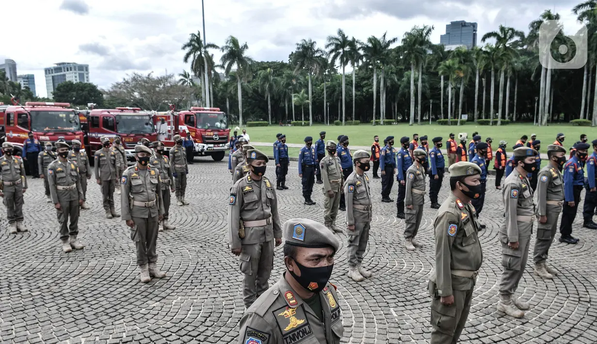 Petugas Satpol PP berbaris saat mengikuti apel Operasi Lilin Jaya 2020 di Lapangan Silang Monas, Jakarta, Senin (21/12/2020). Operasi Lilin dilakukan serentak di seluruh wilayah Indonesia. (merdeka.com/Iqbal S. Nugroho)