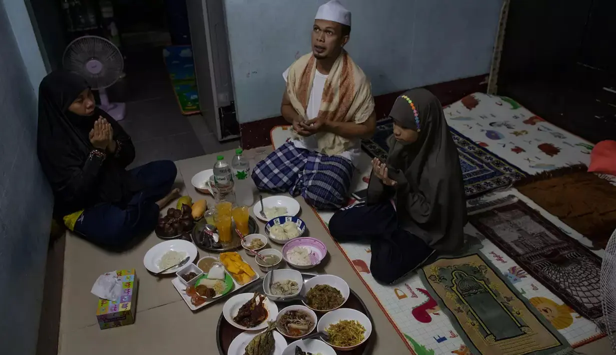 Sebuah keluarga Muslim Thailand berdoa sebelum berbuka puasa di ruang tamu rumah mereka di Bangkok, pada 28 April 2020. Banyak tempat ibadah ditutup guna membendung penyebaran Virus Corona COVID-19 ketika Umat Muslim di seluruh dunia menyambut bulan suci Ramadan. (AP Photo/Gemunu Amarasinghe)