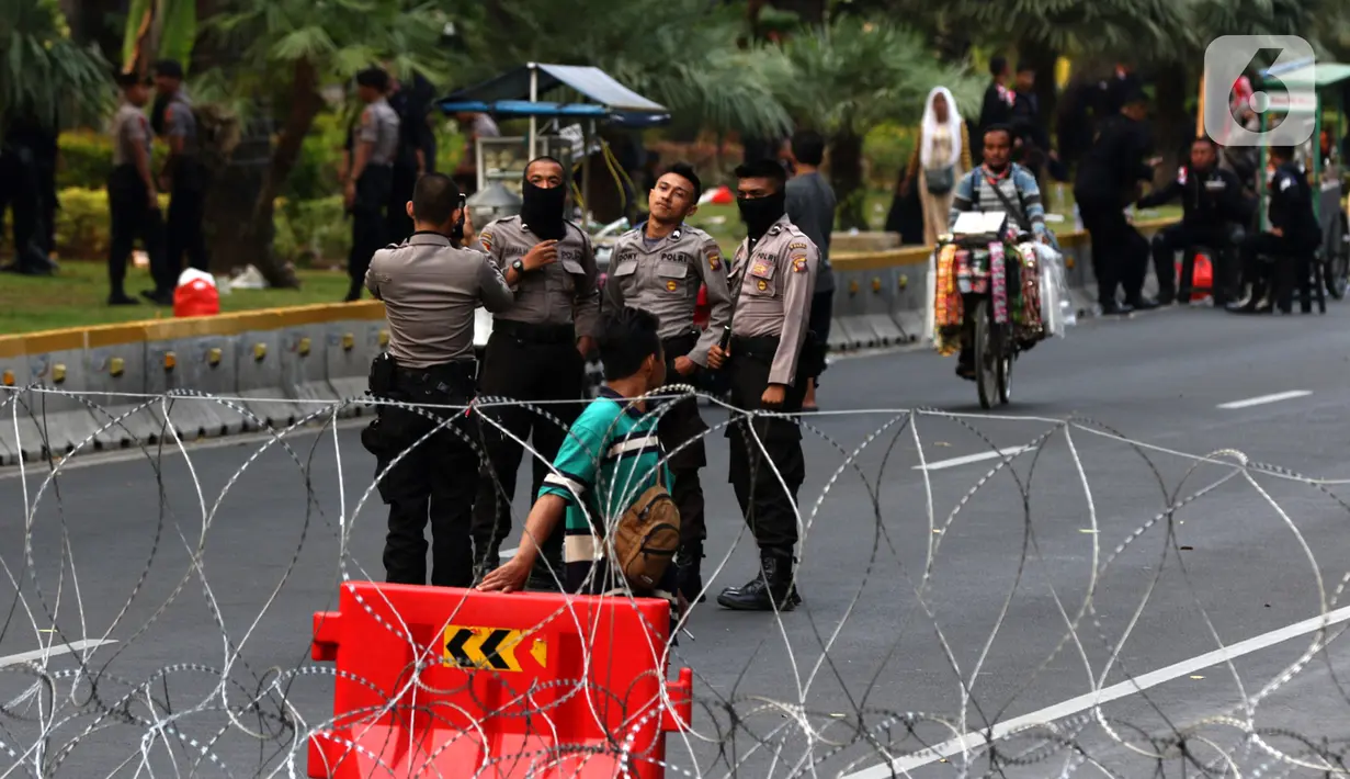 Polisi foto bersama saat menjaga akses jalan menuju Istana Negara, Jakarta, Senin (14/10/2019). Hingga sore hari, polisi masih menutup jalan dikarenakan isu adanya demo mahasiswa yang akan berlangsung hari ini. (Liputan6.com/JohanTallo)