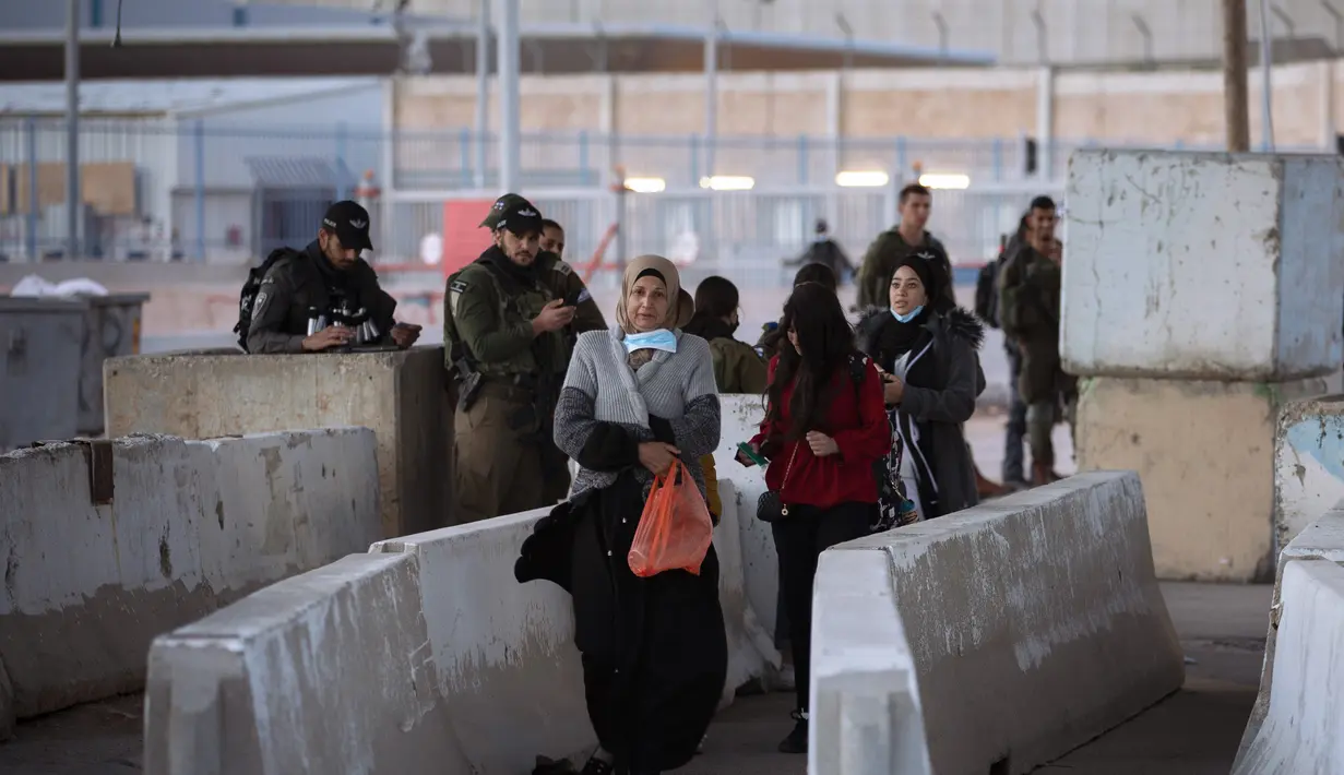 Tentara Israel memeriksa seorang perempuan Palestina saat dia menunggu untuk menyeberangi pos pemeriksaan Qalandia antara kota Ramallah Tepi Barat dan Yerusalem, untuk menghadiri sholat Jumat kedua bulan suci Ramadhan di Masjid Al-Aqsa, Jumat (23/4/2021). (AP Photo/Majdi Mohammed)