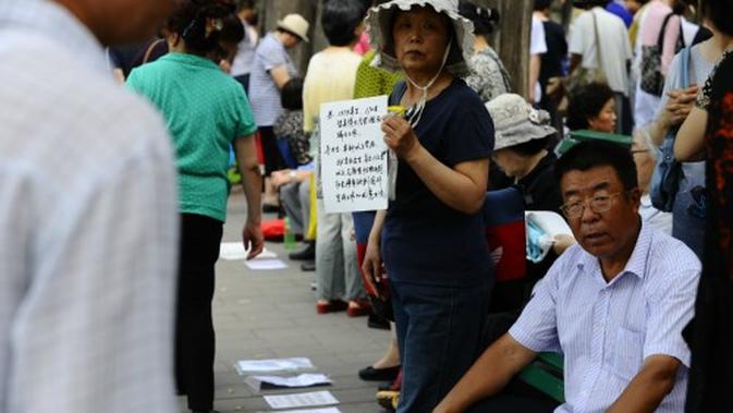 (Foto: © Women of China/Zhang Jiamin) Seorang ibu sedang memegang profil anaknya di taman perjodohan Zhongshan.