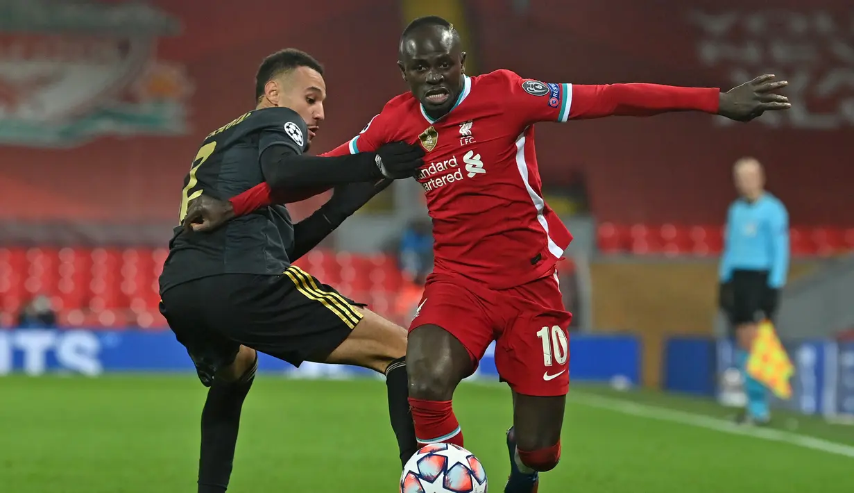 Striker Liverpool, Sadio Mane (kanan), berebut bola dengan bek Ajax Amsterdam, Noussair Mazraoui, dalam laga lanjutan Liga Champions 2020/21 Grup D di Anfield Stadium, Liverpool, Selasa (1/12/2020) waktu setempat. Liverpool menang 1-0 atas Ajax. (AFP/Paul Ellis /Pool)