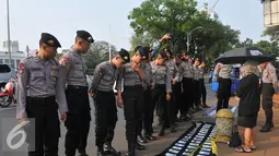 Aparat kepolisian melihat foto-foto yang pajang saat aksi kamisan di depan Istana Negara, Jakarta, Kamis (2/7/15). Dalam aksinya mereka meminta kepada Jokowi untuk menuntaskan kasus pembunuhan Jopi. (Liputan6.com/Herman Zakharia)