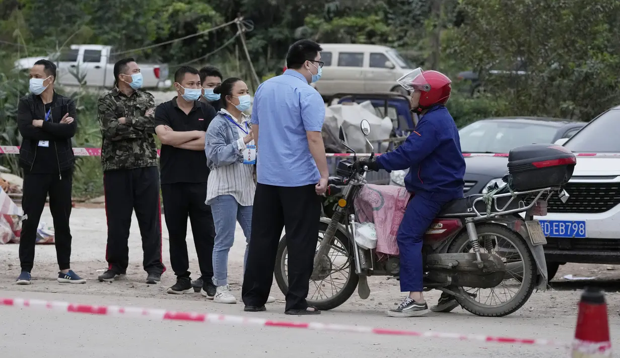 Petugas pemerintah mengontrol akses di pintu masuk desa Lu mengarah ke lokasi jatuhnya pesawat China Eastern di Guangxi, China barat daya, Selasa (23/3/2022). Kecelakaan pesawat dengan 132 orang di dalamnya itu memicu api yang cukup besar dan terlihat pada citra satelit NASA. (AP Photo/Ng Han Guan)