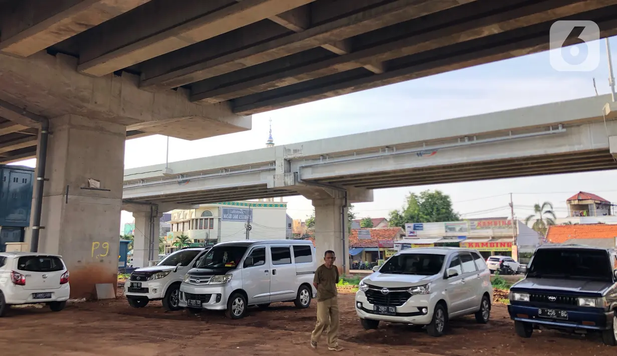 Warga berjalan dekat mobil yang parkir di kolong jalan tol Becakayu di kawasan Cipinang Muara, Jakarta, Jumat (13/3/2020). Minimnya lahan parkir membuat sebagian orang tetap memarkirkan kendaraannya di kolong tol tersebut, meskipun telah terpampang larangan parkir. (Liputan6.com/Immanuel Antonius)