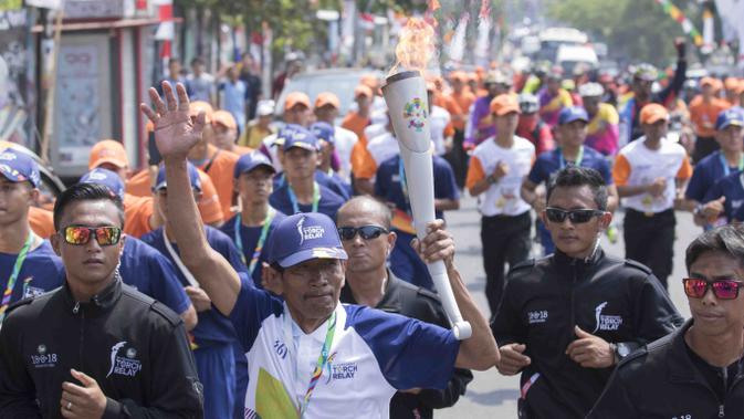 Legenda balap sepeda Indonesia, Sutiono, membawa obor pada pawai Asian Games di Bandar Lampung, Rabu (8/8/2018). (Bola.com/Reza Bachtiar)