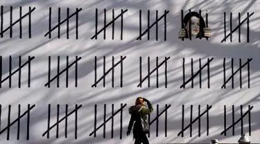 Seorang wanita pejalan kaki melihat mural baru karya seniman misterius Inggris, Banksy di wilayah Manhattan, New York (15/3). Mural ini memprotes penahanan seniman Turki Zehra Dogan karena lukisannya. (AFP Photo/Timothy A. Kliit)