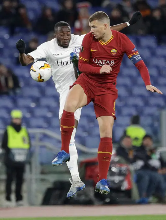 Pemain AS Roma Edin Dzeko (kanan) berebut bola dengan pemain Gent Elisha Owusu pada leg pertama babak 32 besar Liga Europa di Olympic Stadium, Roma, Italia, Kamis (20/2/2020). Gol tunggal Carles Peres membawa AS Roma menaklukkan Gent 1-0. (AP Photo/Gregorio Borgia)