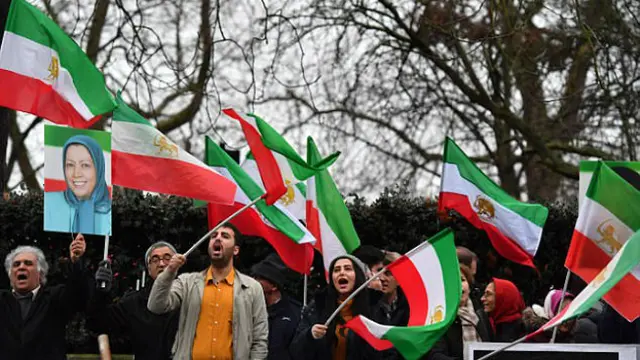 Anggota Mujahidin Iran atau MEK memegang bendera Iran era-Syah Pahlevi (sebelum Revolusi Islam) dan Pemimpin MEK Marjam Rajavi (AFP PHOTO)
