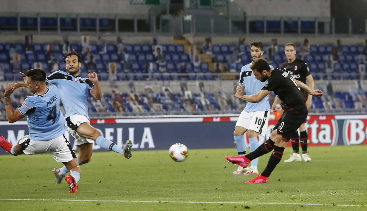 Pemain AC Milan Hakan Calhanoglu (kanan) mencetak gol ke gawang Lazio pada pertandingan Serie A di Olympic Stadium, Roma, Italia, Sabtu (4/7/2020). AC Milan mengalahkan Lazio dengan skor 3-0. (AP Photo/Riccardo De Luca)