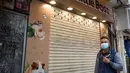 Seseorang melewati toko hewan peliharaan tempat seorang karyawan dan pelanggan dinyatakan positif Covid-19 setelah menangani hamster di Causeway Bay, Hong Kong pada 18 Januari 2022,  memicu rencana pemusnahan lebih dari 1.000 hewan kecil usai beberapa hamster dinyatakan positif. (Bertha WANG/AFP)