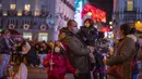 Orang-orang yang memakai masker menikmati lampu Natal di pusat kota Madrid, Rabu (22/12/2021). PM Spanyol Pedro Sanchez mengadakan rapat Kabinet khusus untuk mengesahkan undang-undang yang mewajibkan penggunaan masker di luar ruangan di tengah lonjakan rekor kasus COVID-19. (AP Photo/Manu Fernandez)