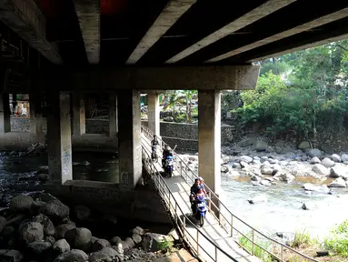 Pengendara motor melewati jembatan Ciliwung yang berada di bawah tol ruas Gadog, Ciawi, Bogor (16/68). Jembatan ini menjadi jalan alternatif bagi pemotor dari kawasan Bogor menuju arah Puncak dan Sukabumi. (Merdeka.com/Arie Basuki)