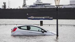 Sebuah mobil terendam air banjir setelah badai di Hamburg, Jerman, Minggu (30/1/2022).Badai musim dingin yang kuat melanda Eropa utara selama akhir pekan. (Daniel Bockwoldt/dpa via AP)