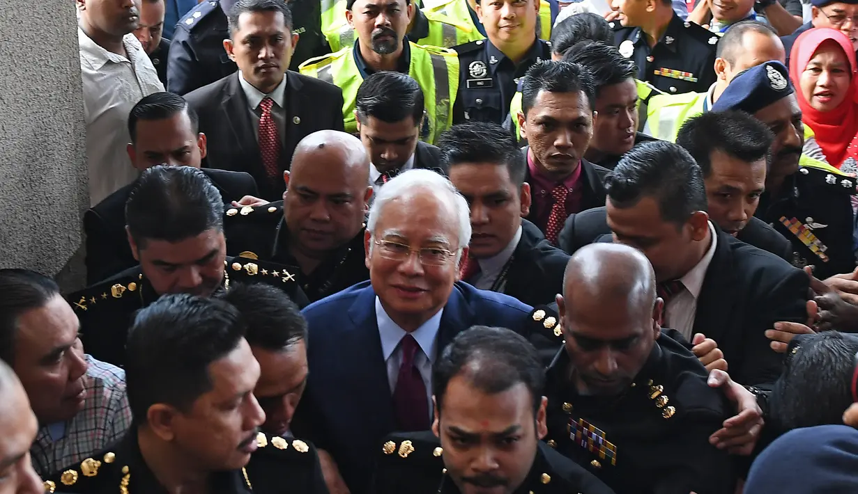 Mantan Perdana Menteri Malaysia, Najib Razak dengan pengawalan ketat tiba di Pengadilan Kuala Lumpur untuk didakwa pertama kalinya, Rabu (4/7). Jaksa Agung Tommy Thomas akan memimpin tim jaksa dalam kasus skandal mega korupsi 1MDB. (AFP/MOHD RASFAN)