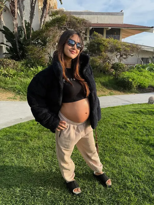 Berlibur ke California, Aurelie Moeremans tampil santai namun tetap stylish. Ia memadukan crop top hitam dengan jogger pants nude, lalu menyempurnakannya dengan jaket bulu hitam. Look ini memberi kesan sporty-chic yang nyaman, sekaligus menonjolkan baby bump dengan percaya diri. [@aurelie].