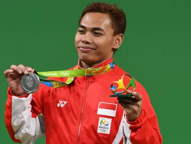 Lifter Indonesia, Eko Yuli Irawan berpose dengan medali perak di atas podium cabang olahraga angkat besi 62 KG selama Olimpiade 2016 di Rio De Janeiro, Senin (8/8). Atlet Eko Yuli mempersembahkan medali perak bagi kontingen Indonesia. (GOH Chai Hin/AFP)