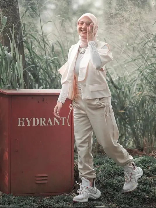 Tampil chic namun tetap sporty, Irish memadukan vest dengan inner putih dan jogger pants krem. Sneakers putih jadi paduan yang pas. (Instagram/_irishbella_).
