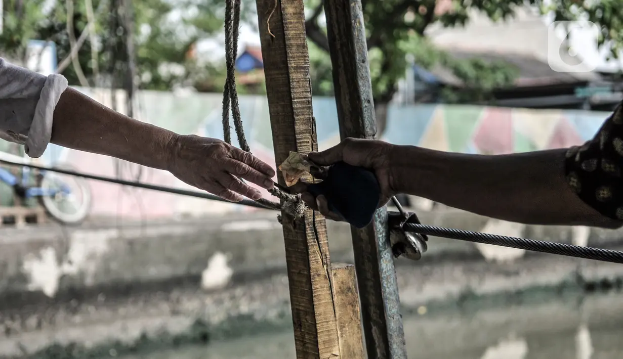 Hendi (40) saat menerima uang dari salah satu penumpang perahu eretan di Kali Sunter, Rawa Badak, Jakarta, Rabu (20/1/2021). Jasa perahu eretan di Rawa Badak sudah ada sejak tahun 80-an dengan kondisi kali yang masih lebar. (merdeka.com/Iqbal S. Nugroho)
